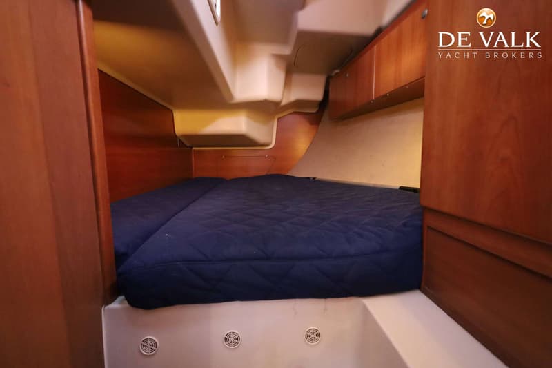 Een kajuit met een donkerblauw matras, houten wanden en een wit plafond met ventilatieroosters. — Dehler 41 Cruising
