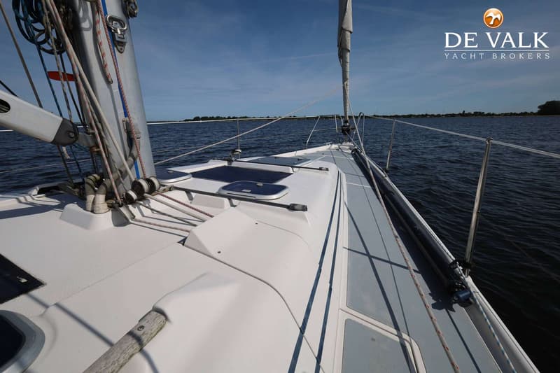 Een zeilboot op het water, gezien vanaf het dek naar voren, met een mast en zeil, en een blauwe lucht. — Dehler 41 Cruising