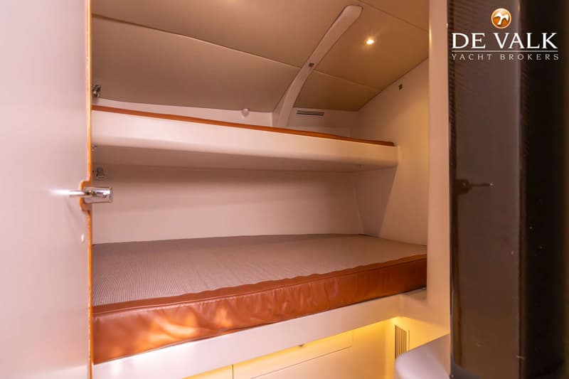 De foto toont een kajuit met twee bedden boven elkaar, waarvan het onderste bed een bruin leren matras heeft.