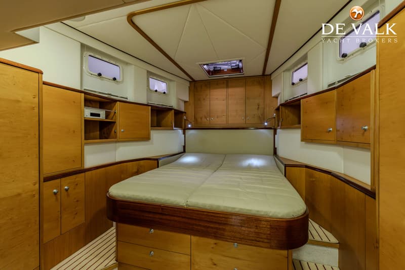 De foto toont een kajuit met een tweepersoonsbed, houten kasten en lades, patrijspoorten en een dakluik. — Jetten Custom