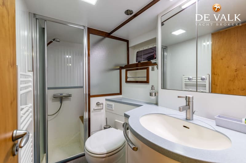 Een badkamer met een douchecabine, toilet, wastafel met kraan en een spiegelkast.