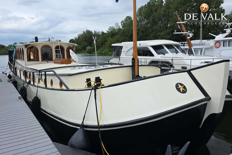 Een zwart-witte boot met een gouden ster op de boeg ligt aangemeerd aan een houten steiger. — Luxe motor 1900