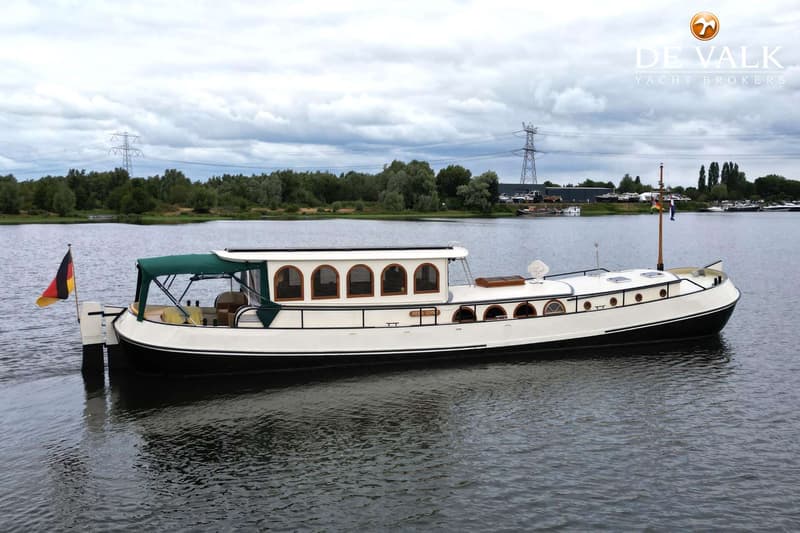 Een witte boot met een zwarte romp en een groene bimini vaart op het water onder een bewolkte hemel. — Luxe motor 1900