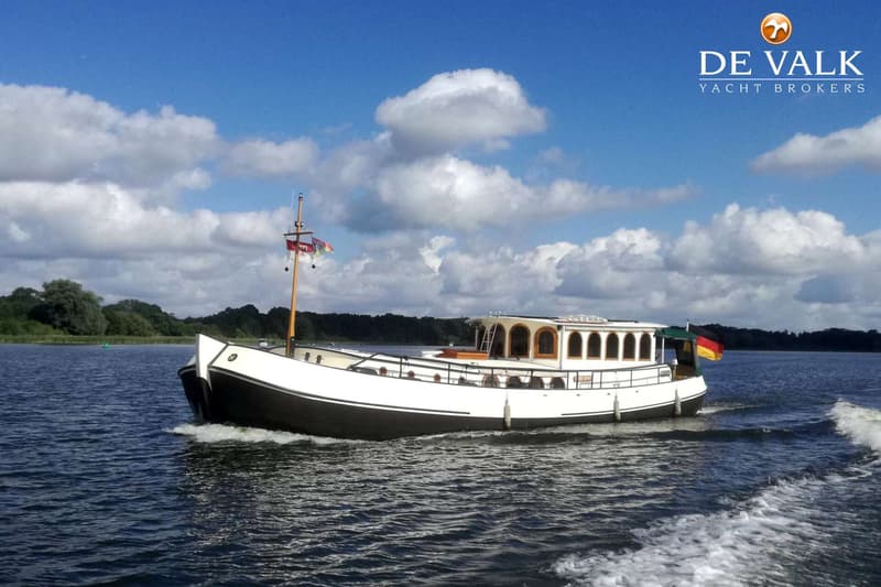 Een witte boot met een zwarte romp vaart over het water onder een blauwe lucht met witte wolken. — Luxe motor 1900