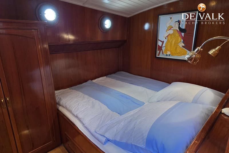 Een slaapkamer met een tweepersoonsbed, twee patrijspoorten, een schilderij en een kledingkast.