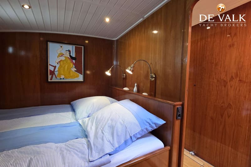 Een slaapkamer met een bed met blauw-wit gestreepte kussens en dekens, houten wanden en een schilderij.