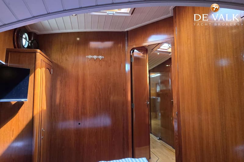 Een interieur van een boot met houten wanden, een patrijspoort, een kledingkast, een tv en een open deur. — Luxe motor 1900