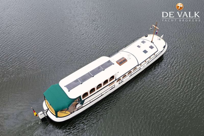 Een witte boot met een groen dekzeil en zonnepanelen op het dak vaart op donker water. — Luxe motor 1900
