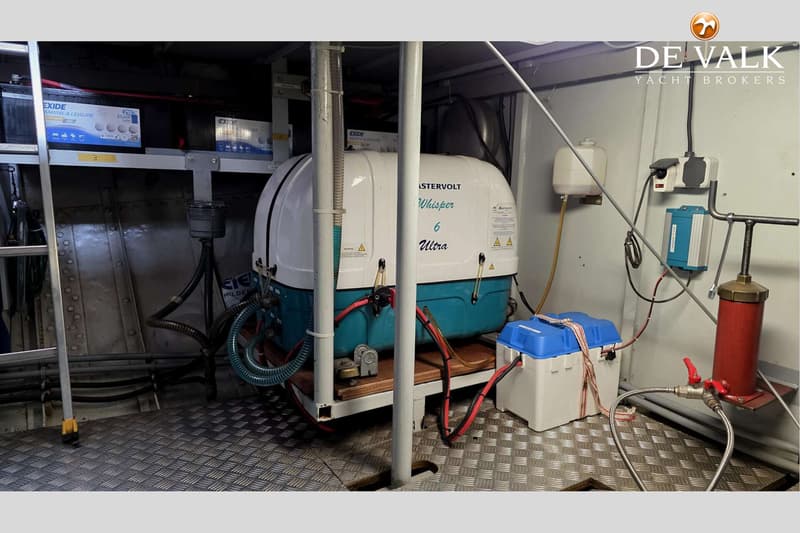 Een machinekamer met een Mastervolt Whisper 6 Ultra generator, Exide accu's en diverse leidingen en apparatuur.