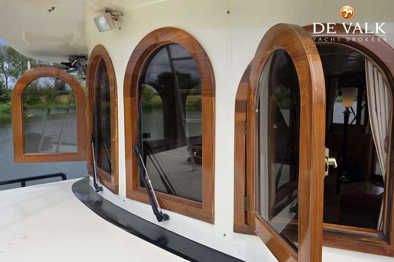 De foto toont de zijkant van een boot met drie houten ramen, waarvan er twee open staan. — Luxe motor 1900