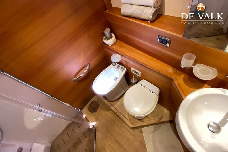 Een badkamer met houten wanden en vloer, met een bidet, toilet, wastafel en een douchecabine.