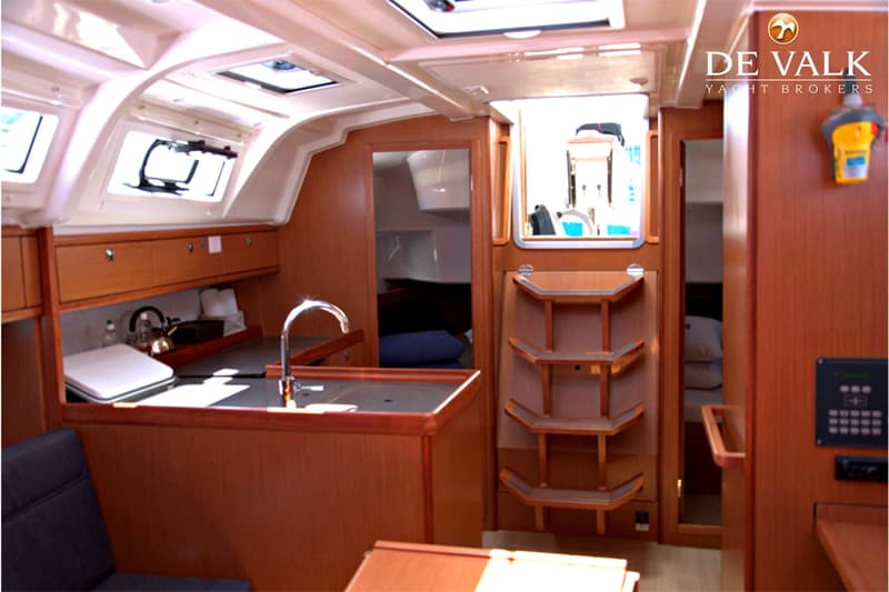 De foto toont het interieur van een boot met een kombuis, een trap en een doorgang naar een andere ruimte.