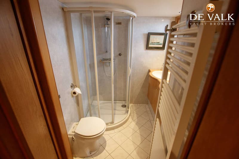 Een badkamer met een toilet, een douchecabine, een wastafel met houten kastje en een handdoekradiator.