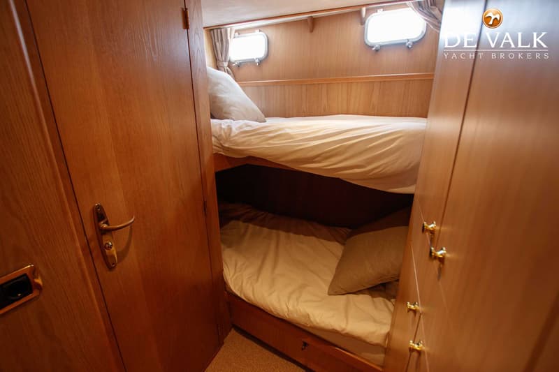 De foto toont een kajuit met twee stapelbedden, twee patrijspoorten en houten wanden. — Kompier Canoe Stern 1650 Trawler