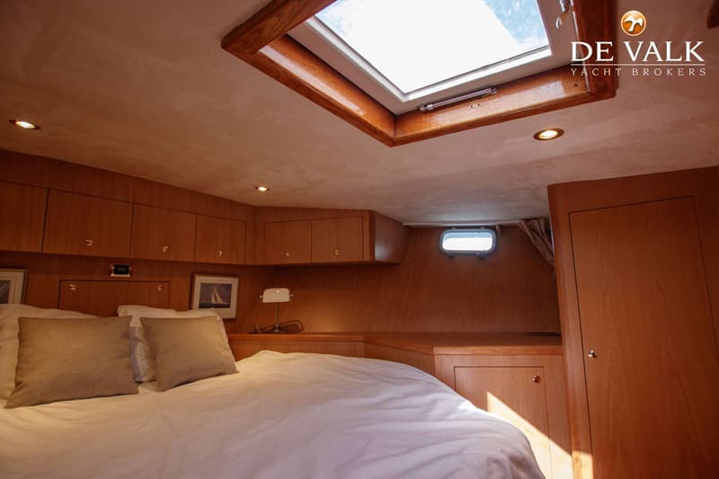 Een kajuit met een bed, houten wanden en kasten, een dakraam en een patrijspoort. — Kompier Canoe Stern 1650 Trawler
