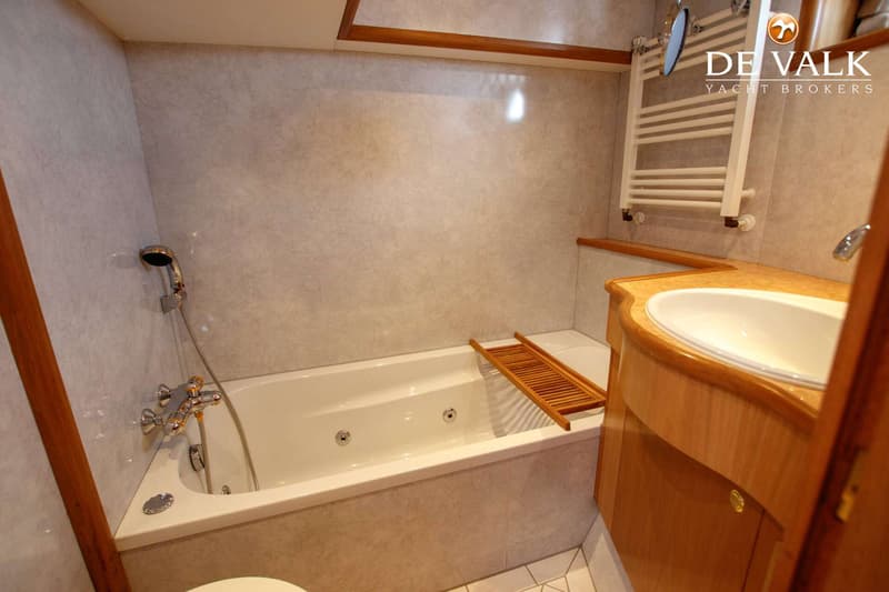 Een badkamer met een wit bad, een wastafel in een houten meubel en een handdoekrek.