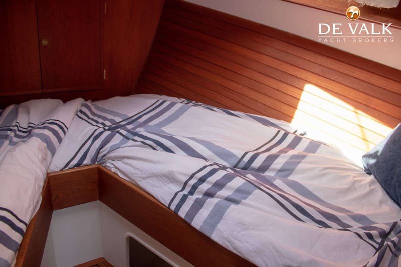 Een kajuit met een bed met gestreept dekbedovertrek en houten wanden. — Bloemsma Zeilkotter Aluminium