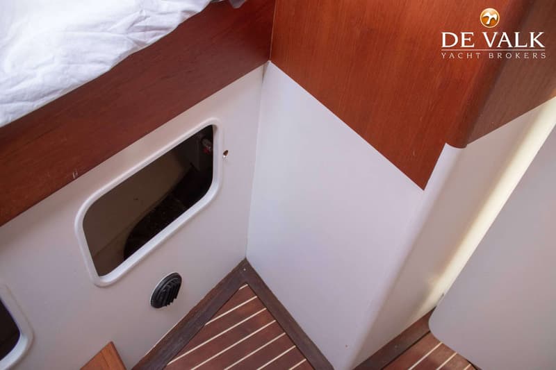 Een interieur van een boot met houten en witte panelen, een houten vloer en een wit laken. — Bloemsma Zeilkotter Aluminium