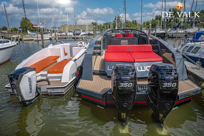 Twee boten liggen aangemeerd in een haven, met een witte boot aan de linkerkant en een grijze boot aan de rechterkant.