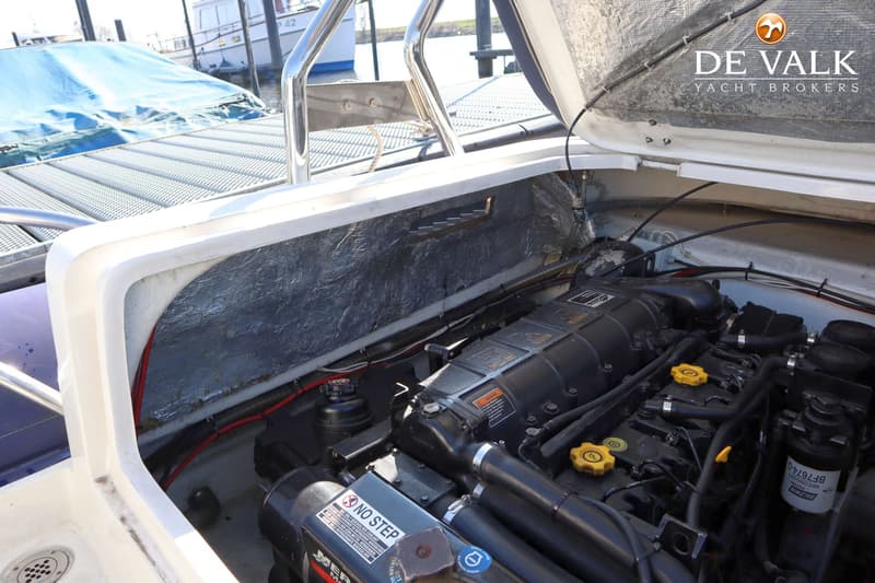 Een open motorruimte van een boot met een zwarte motor, gele doppen en een "NO STEP" waarschuwing. — Arctic Blue 27