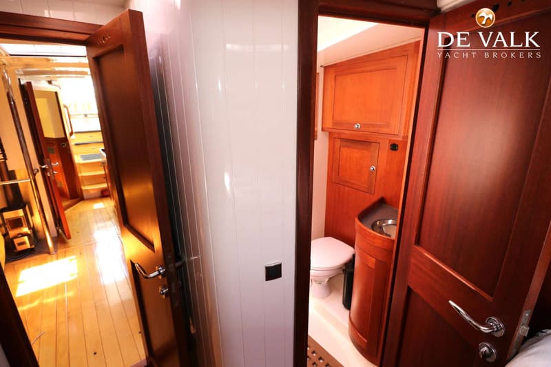 Een interieurfoto van een boot met een gang en een deels zichtbare badkamer met toilet en wasbak. — Bestewind 50 Pilothouse