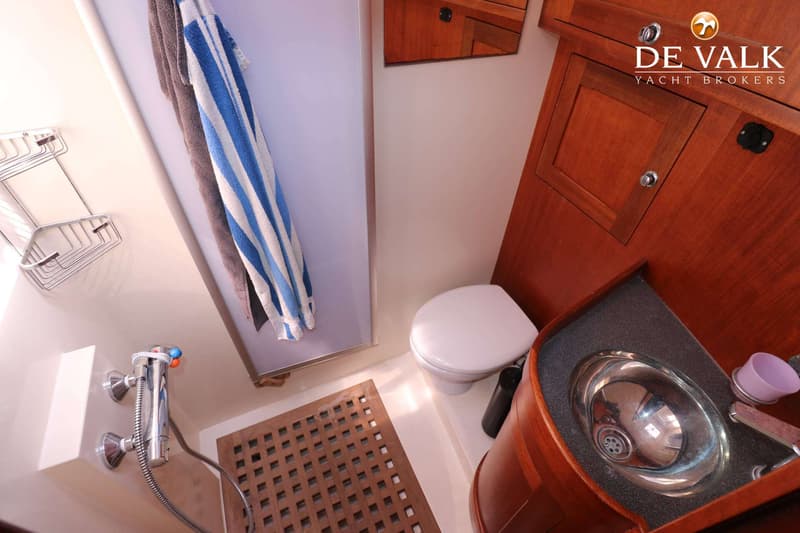 Een badkamer met een douche, toilet en wastafel, met houten accenten en handdoeken.