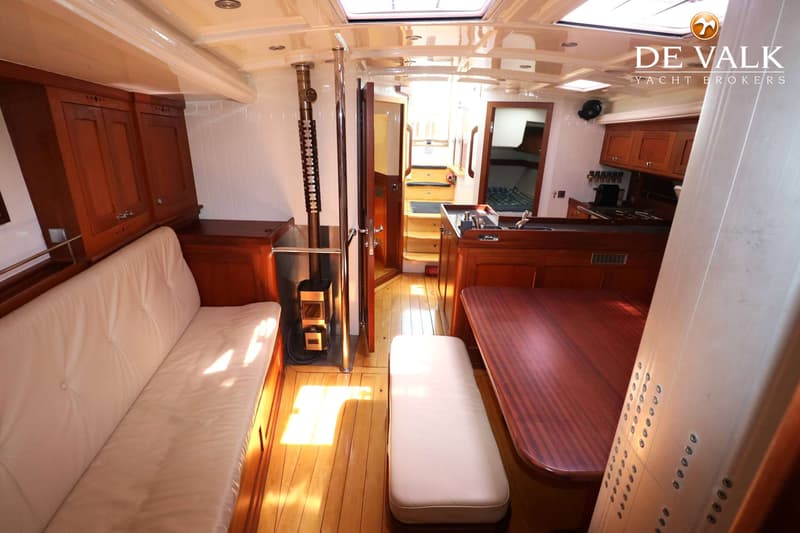 De foto toont het interieur van een boot met houten vloeren, meubels en een zithoek met een tafel. — Bestewind 50 Pilothouse