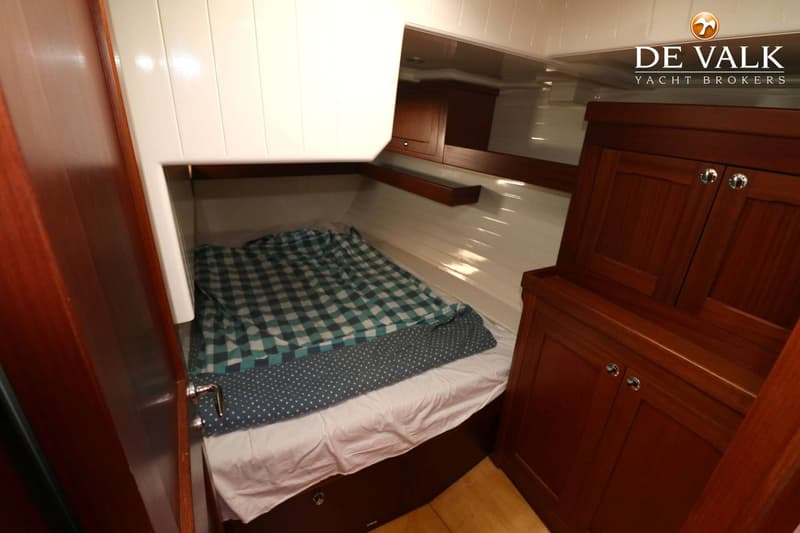 Een kajuit met een bed met geruit dekbed, een wit plafond en houten kasten. — Bestewind 50 Pilothouse