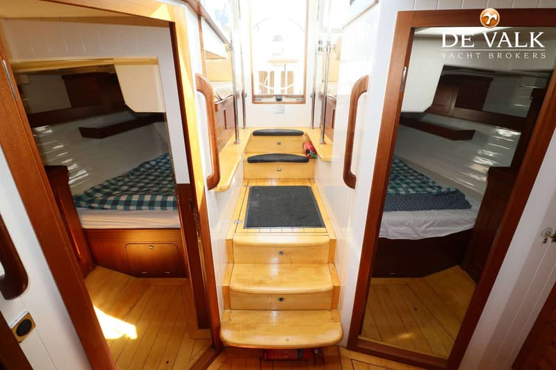 Een houten trap met zwarte matten leidt naar beneden, geflankeerd door twee hutten met geruite dekens.