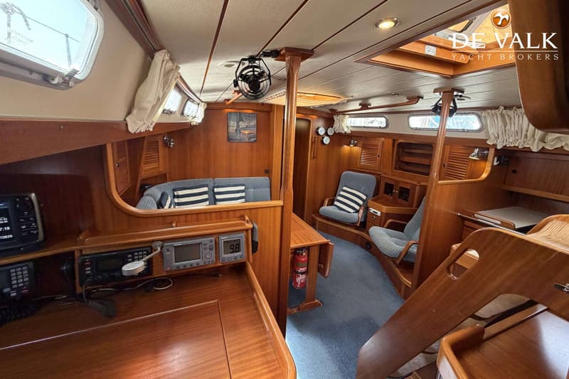 De foto toont het interieur van een boot met houten afwerking, blauwe bekleding en diverse navigatieapparatuur.