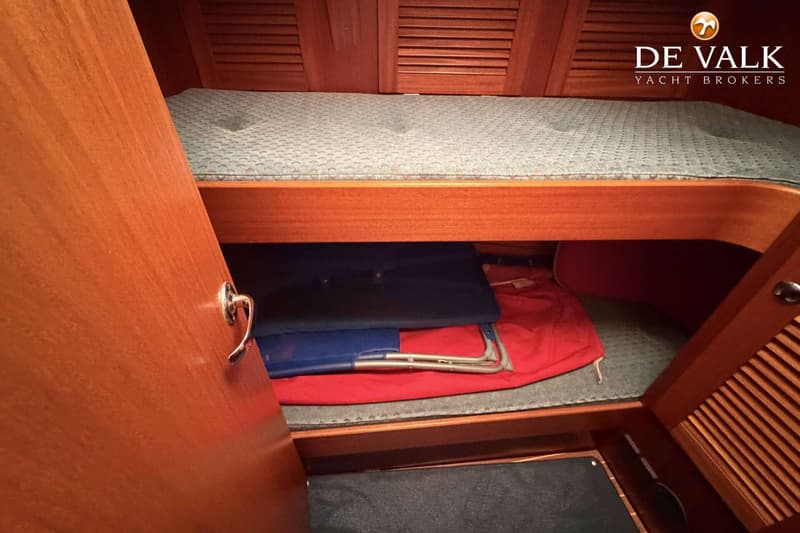 Een kajuit met een bed, opbergruimte en een openstaande houten deur. — Hallberg Rassy 46