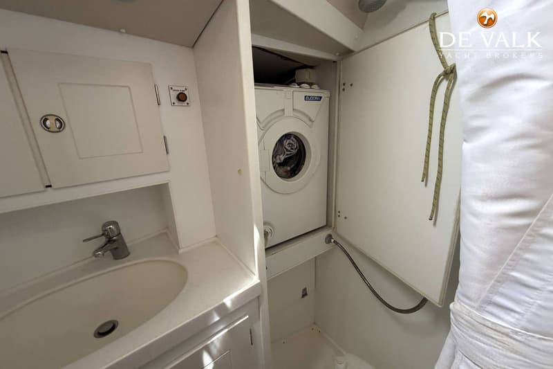 Een witte wasmachine van het merk Eudora is zichtbaar in een kleine ruimte naast een wastafel met kraan.