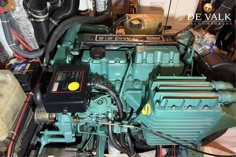 Een detailfoto van een Volvo Penta TAMD 31S scheepsmotor met diverse slangen, kabels en een De Valk Yacht Brokers logo.