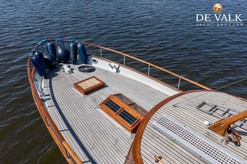 Een bovenaanzicht van het voordek van een boot met houten dek, fenders, luiken en een reling. — Kok Spitsgatkotter 16.50