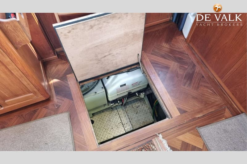 Een open luik in een houten vloer toont een witte generator met "4500" en "Fischer Panda Generators" erop.