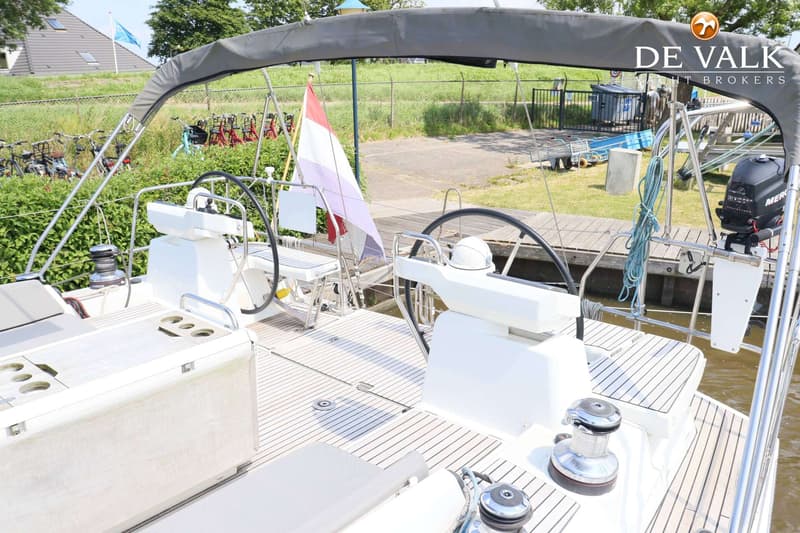Een bovenaanzicht van de kuip van een zeilboot met twee stuurwielen, een Nederlandse vlag en een buitenboordmotor.