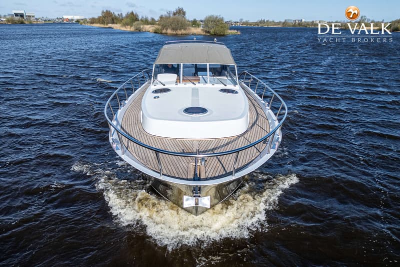 Een witte motorboot met een houten dek en een grijze bimini vaart op donkerblauw water. — Van der Heijden 1350 Cruiser