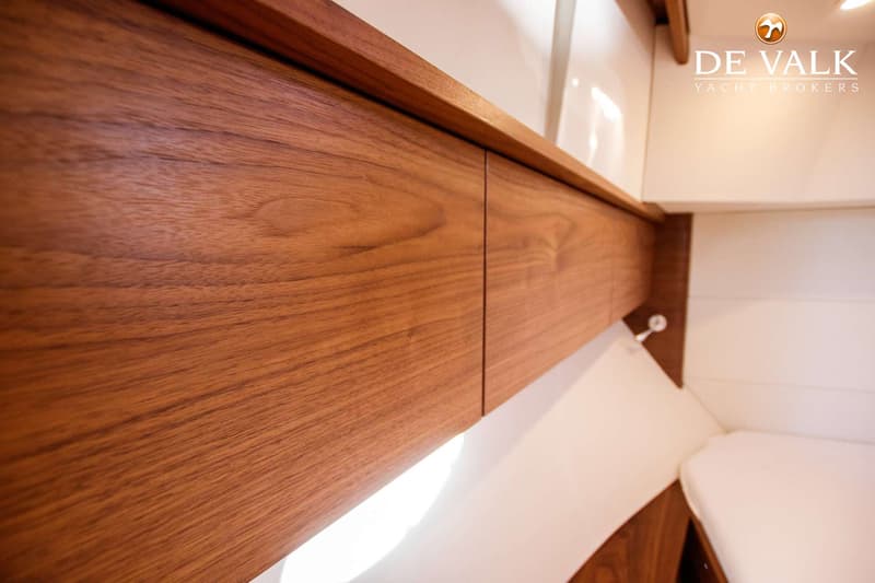 Een detailfoto van een interieur met houten kasten en witte wanden, met een lichtstrip onder de kasten.