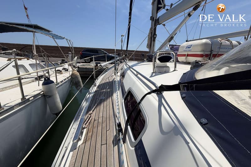 Een zeilboot ligt afgemeerd aan een steiger, met een andere boot ernaast en een auto op de achtergrond. — Bavaria 40 Cruiser