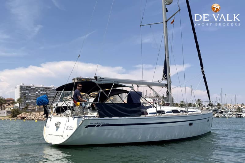 Een witte zeilboot met de tekst "BAVARIA 40 cruiser" en "Köln" op de romp vaart op water onder een blauwe lucht.