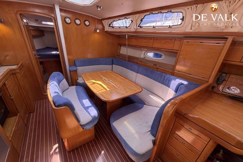 De foto toont het interieur van een boot met een houten tafel, blauw-grijze banken en een houten vloer. — Bavaria 40 Cruiser