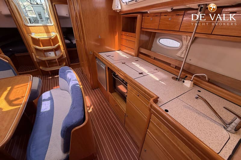 Een interieur van een boot met houten lambrisering, een kombuis met gootsteen en kookplaat, en een zithoek.