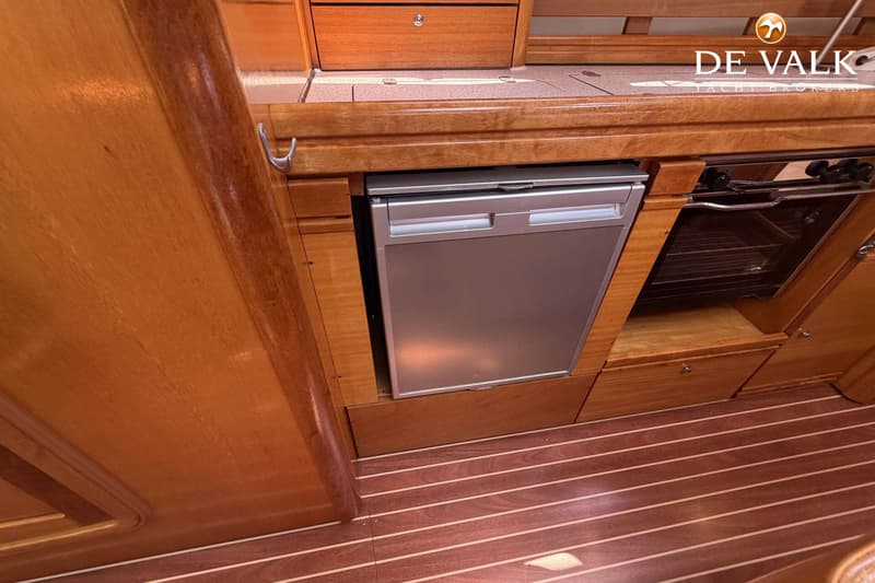 Een zilverkleurige koelkast en een oven zijn ingebouwd in een houten interieur met een gestreepte houten vloer.