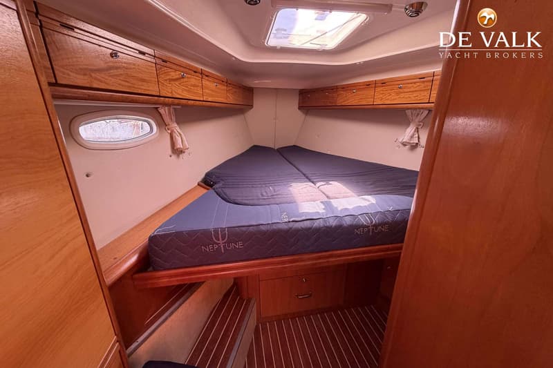 De foto toont een kajuit met een V-vormig bed met twee matrassen, houten kasten en een patrijspoort. — Bavaria 40 Cruiser