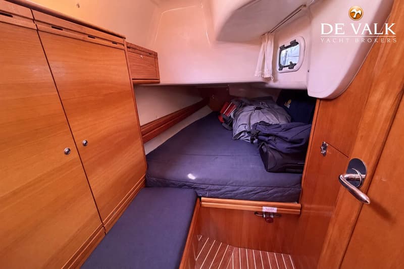 De foto toont een kajuit met een bed, houten kasten en een raam met gordijn. — Bavaria 40 Cruiser