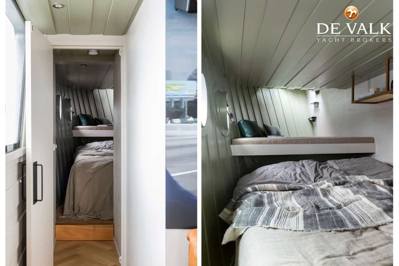 Een kajuit met twee bedden, waarvan één stapelbed, met een houten vloer en een logo van "DE VALK YACHT BROKERS".