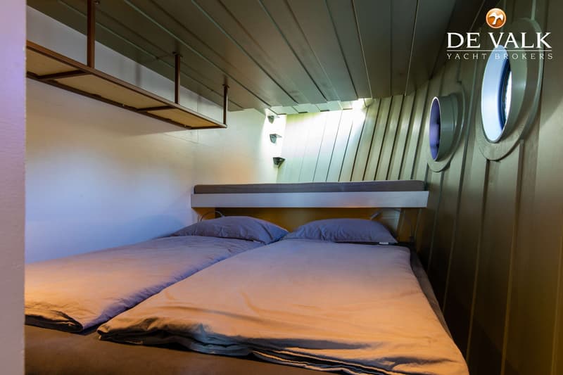 Een kajuit met twee eenpersoonsbedden, een stapelbed erboven, twee patrijspoorten en een plank aan het plafond.