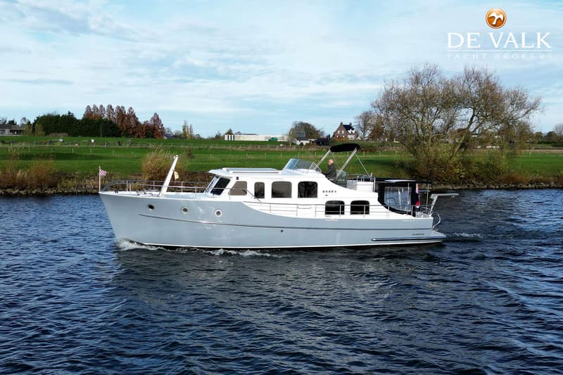 Een grijze motorboot met de naam "KOBRA" vaart op het water, met een persoon aan het roer.