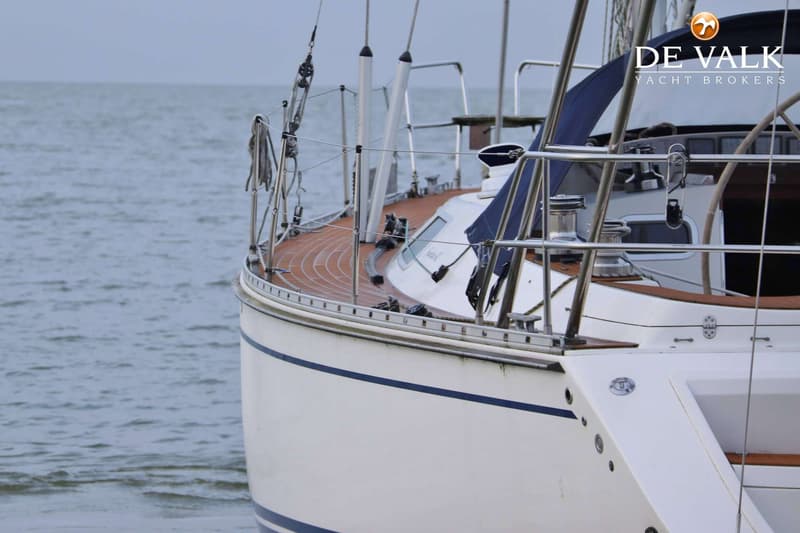 Een witte zeilboot met een teakhouten dek en blauwe strepen op de romp, drijvend op water. — Comfortina 42