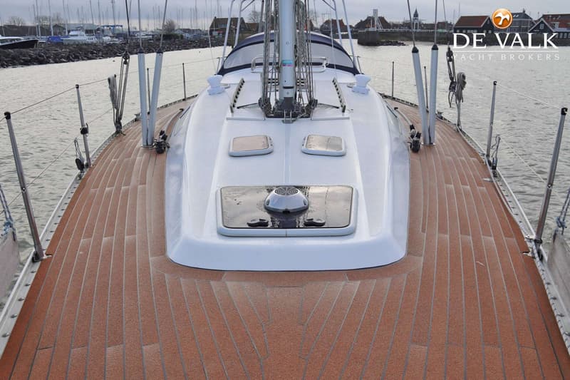 Een bovenaanzicht van het dek van een zeilboot met een bruine, gestructureerde vloer en witte opbouw. — Comfortina 42